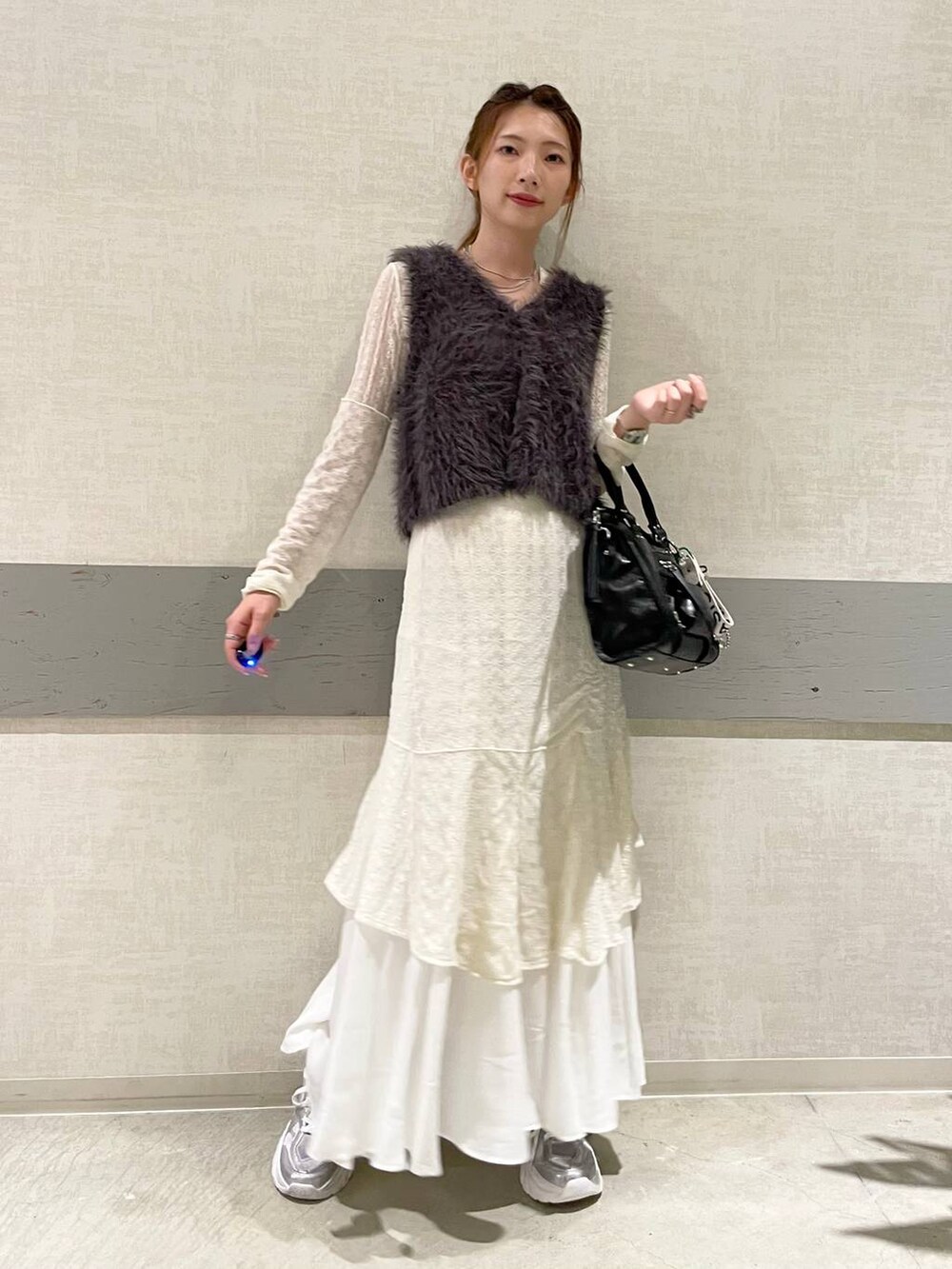 グレー系のベスト、ブラック系のボストンバッグ、シルバー系のスニーカーを着用したレディースの秋コーディネートの3枚目の写真