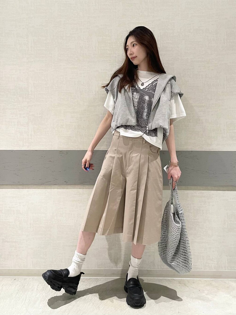 ブラック系のローファー、シルバー系のショルダーバッグ、グレー系のベストを着用したレディースの春コーディネートの5枚目の写真