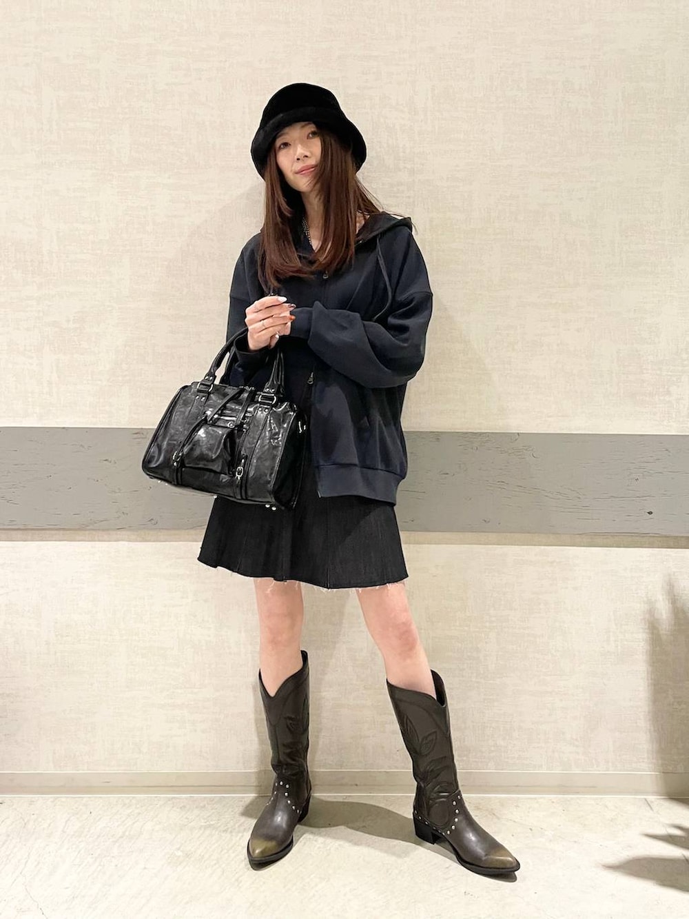 ブラック系のボストンバッグ、ブラック系のブーツ、ブルー系のパーカーを着用したレディースの冬コーディネートの2枚目の写真