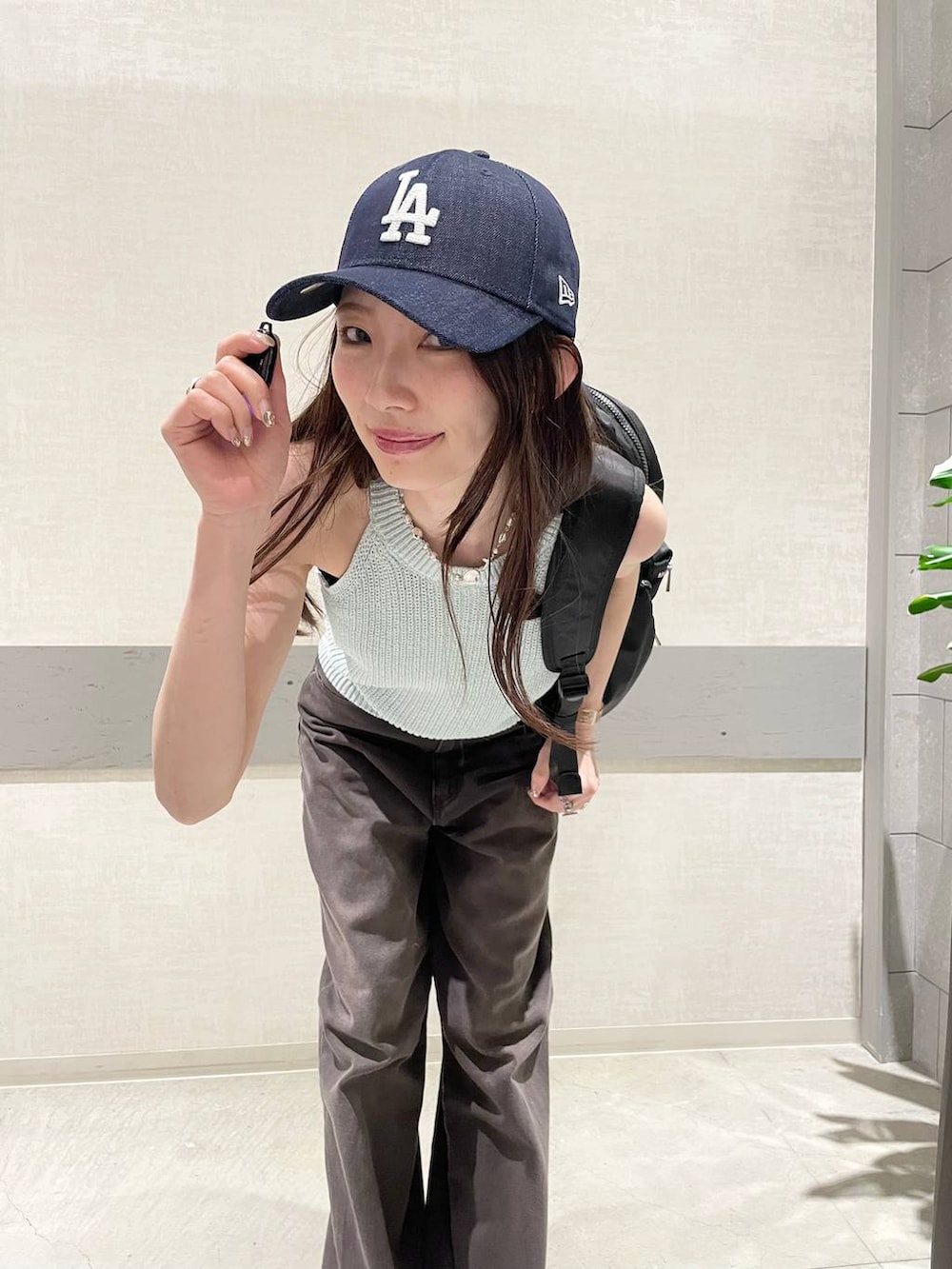 ブラック系のバックパック/リュック、グリーン系のタンクトップ、ブラウン系のデニムパンツを着用したレディースの春コーディネートの6枚目の写真