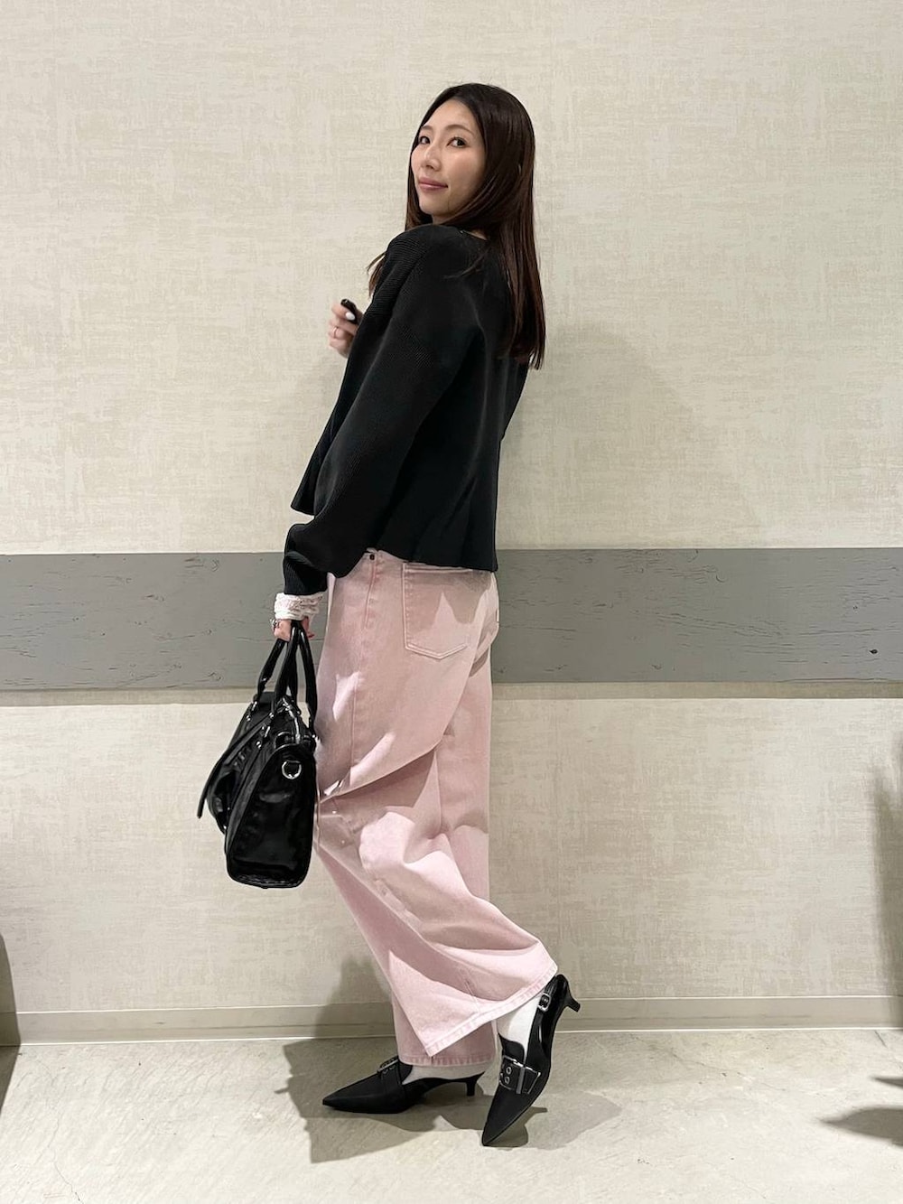 ブラック系のボストンバッグ、ブラック系のパンプス、ピンク系のデニムパンツを着用したレディースの冬コーディネートの3枚目の写真