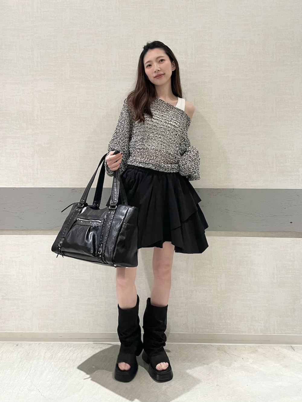 ホワイト系のタンクトップ、ブラック系のトートバッグ、ブラック系のスカートを着用したレディースの春コーディネートの2枚目の写真