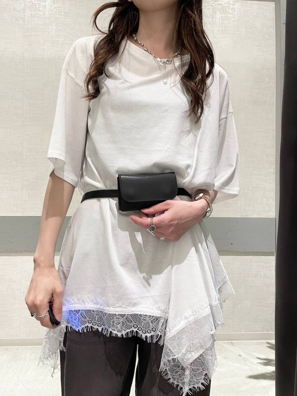 ブラウン系のデニムパンツ、ブラック系のパンプス、ホワイト系のチュニックを着用したレディースの夏コーディネートの6枚目の写真