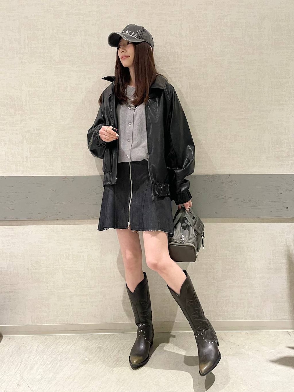 ブラック系のブーツ、グリーン系のボストンバッグ、ブラック系のブルゾンを着用したレディースの冬コーディネートの2枚目の写真