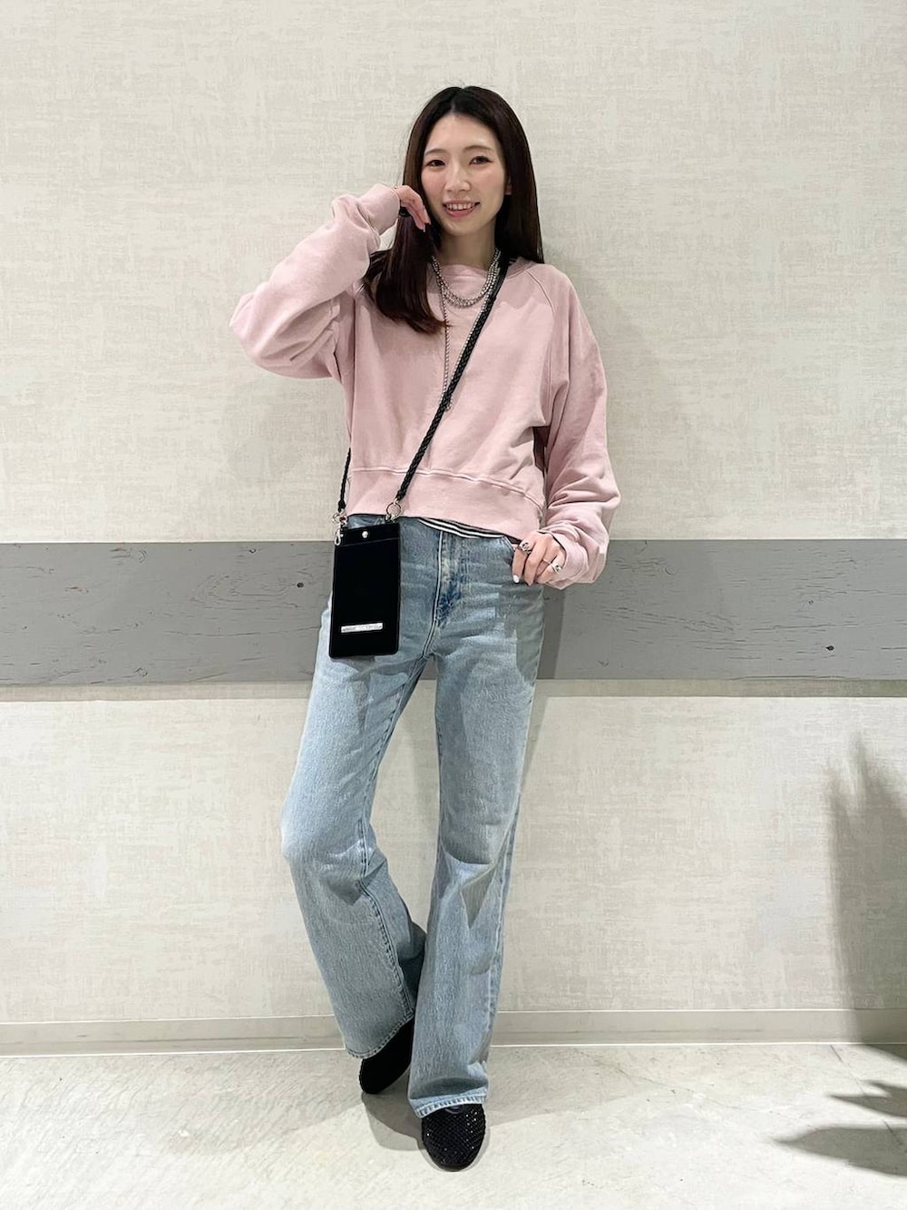 ブラック系のパンプス、ピンク系のスウェット、ブルー系のデニムパンツを着用したレディースの冬コーディネートの3枚目の写真