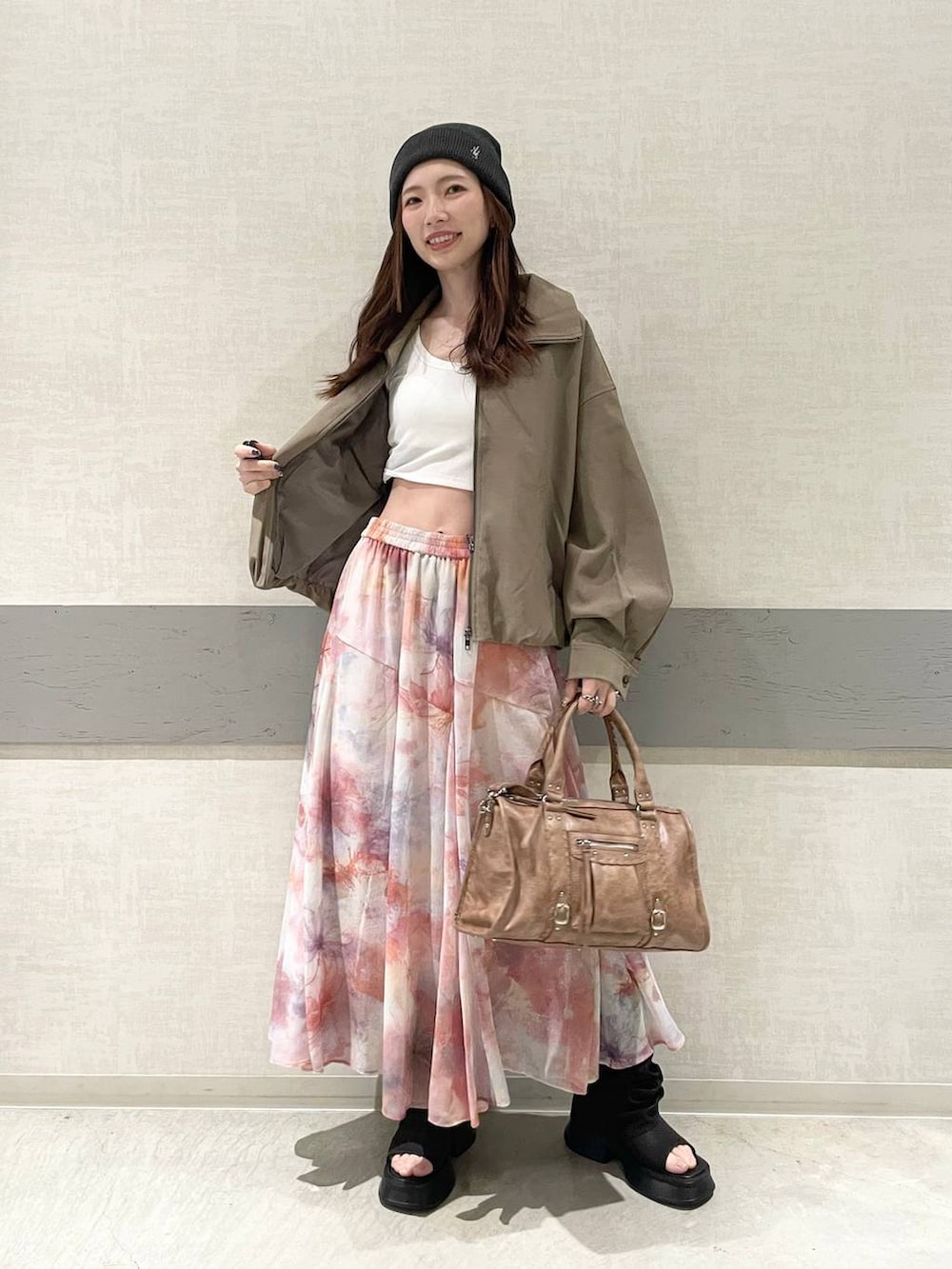 ホワイト系のタンクトップ、ブラウン系のボストンバッグ、ブラウン系のブルゾンを着用したレディースの春コーディネートの3枚目の写真