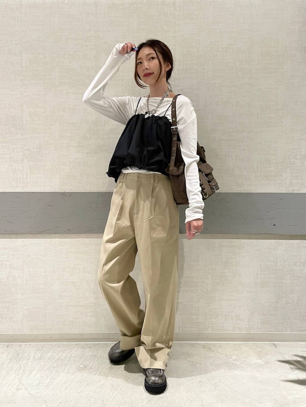 ブラウン系のショルダーバッグ、ブラック系のローファー、ベージュ系のチノパンツを着用したレディースの秋コーディネートの2枚目の写真