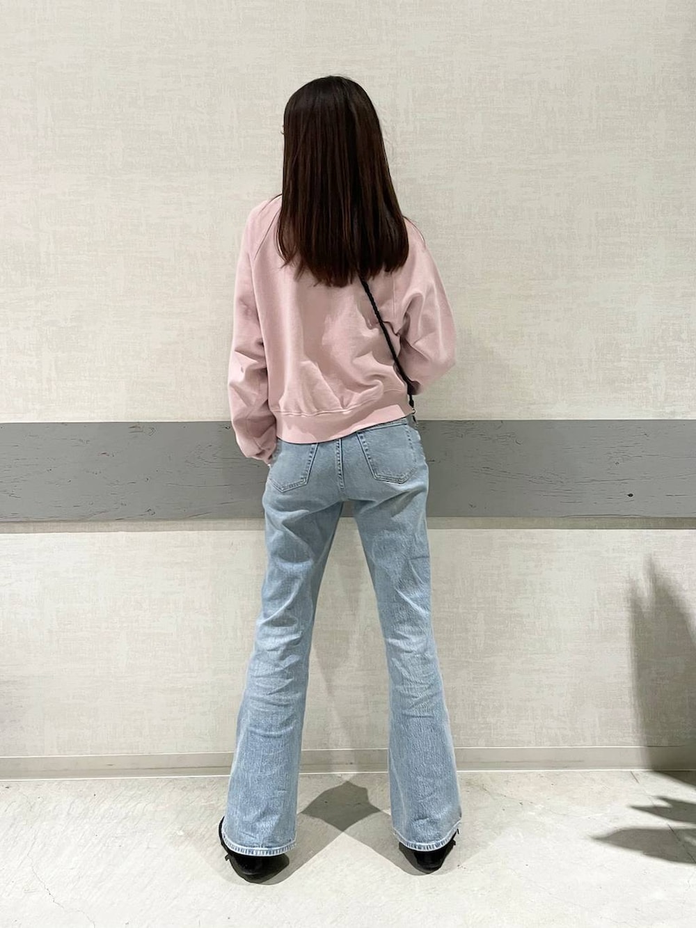 ブラック系のパンプス、ピンク系のスウェット、ブルー系のデニムパンツを着用したレディースの冬コーディネートの4枚目の写真