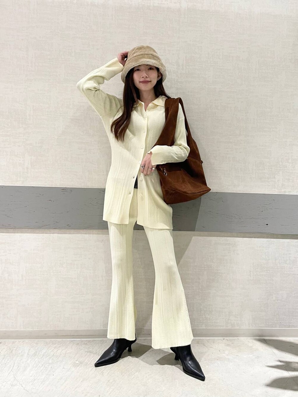 ブラック系のブーツ、ブラウン系のトートバッグ、イエロー系のセットアップを着用したレディースの冬コーディネートの3枚目の写真