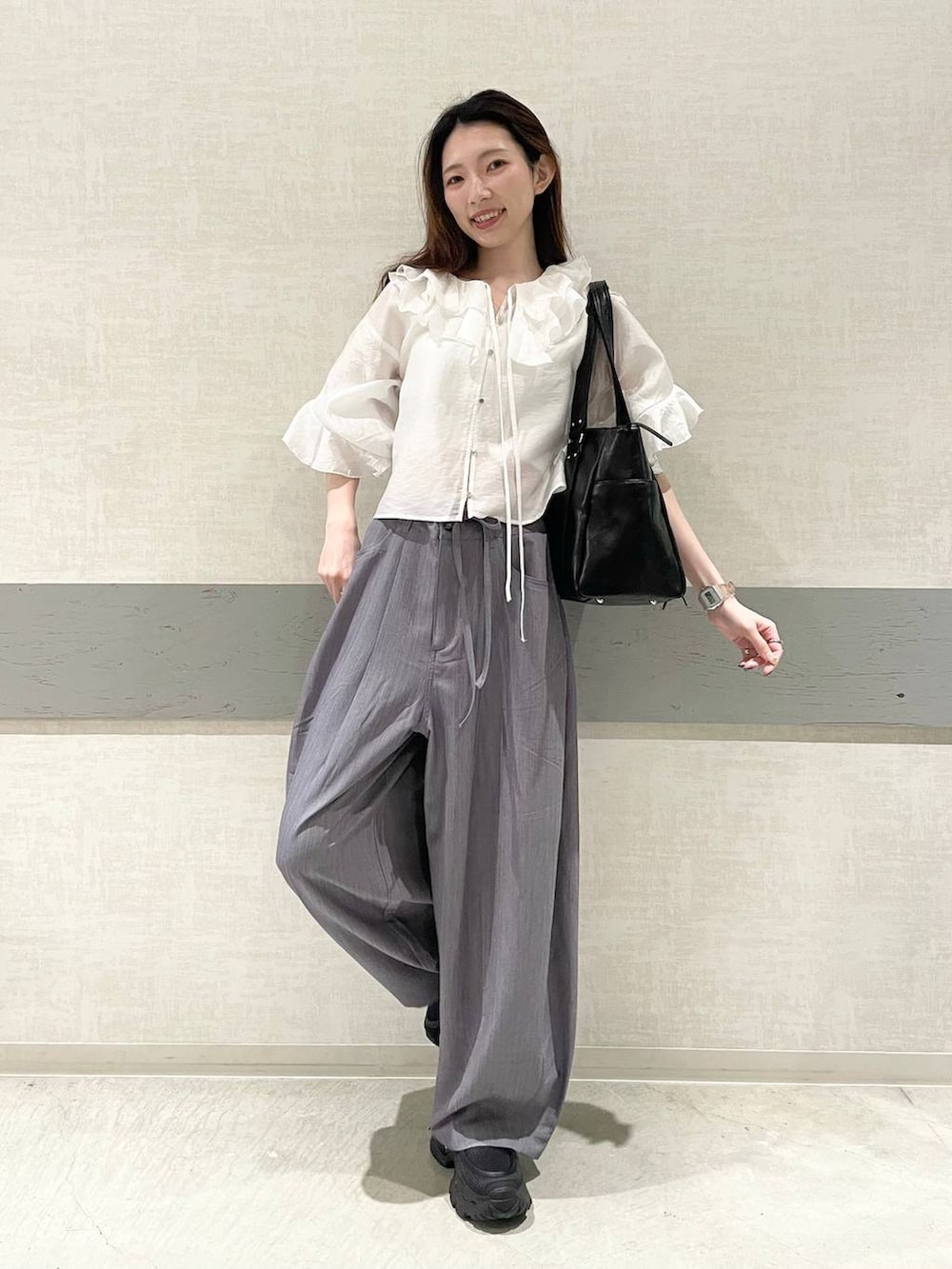 ブラック系のローファー、ブラック系のトートバッグ、グレー系のスラックスを着用したレディースの春コーディネートの2枚目の写真