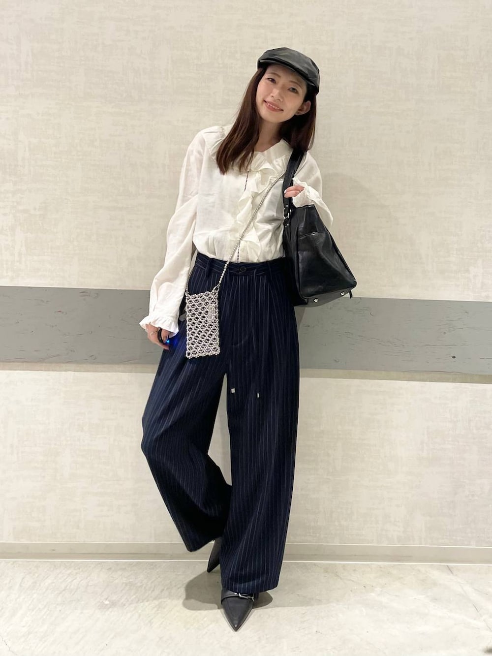 ブラック系のパンプス、ブルー系のスラックス、ブラック系のトートバッグを着用したレディースの春コーディネートの2枚目の写真