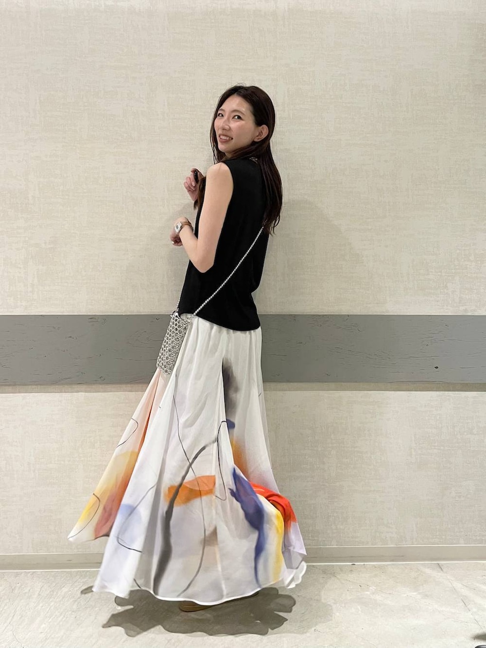 ホワイト系のスカート、ベージュ系のローファー、ブラック系のTシャツ/カットソーを着用したレディースの夏コーディネートの2枚目の写真