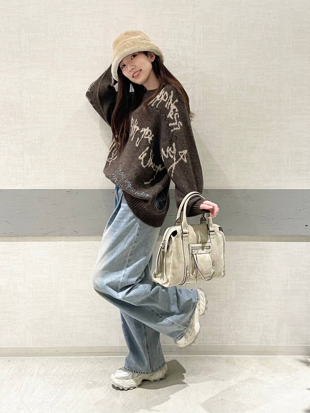 ブルー系のデニムパンツ、ホワイト系のスニーカー、ベージュ系のボストンバッグを着用したレディースの冬コーディネートの2枚目の写真