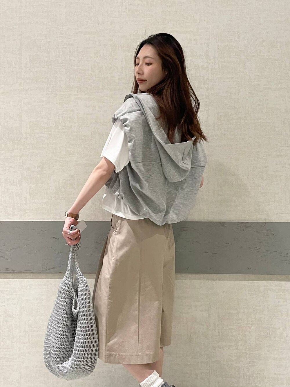 ブラック系のローファー、シルバー系のショルダーバッグ、グレー系のベストを着用したレディースの春コーディネートの3枚目の写真