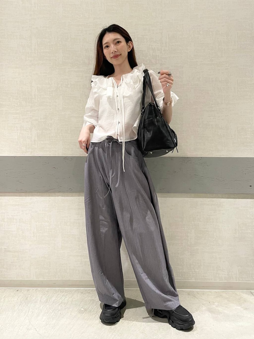 ブラック系のローファー、ブラック系のトートバッグ、グレー系のスラックスを着用したレディースの春コーディネートの3枚目の写真