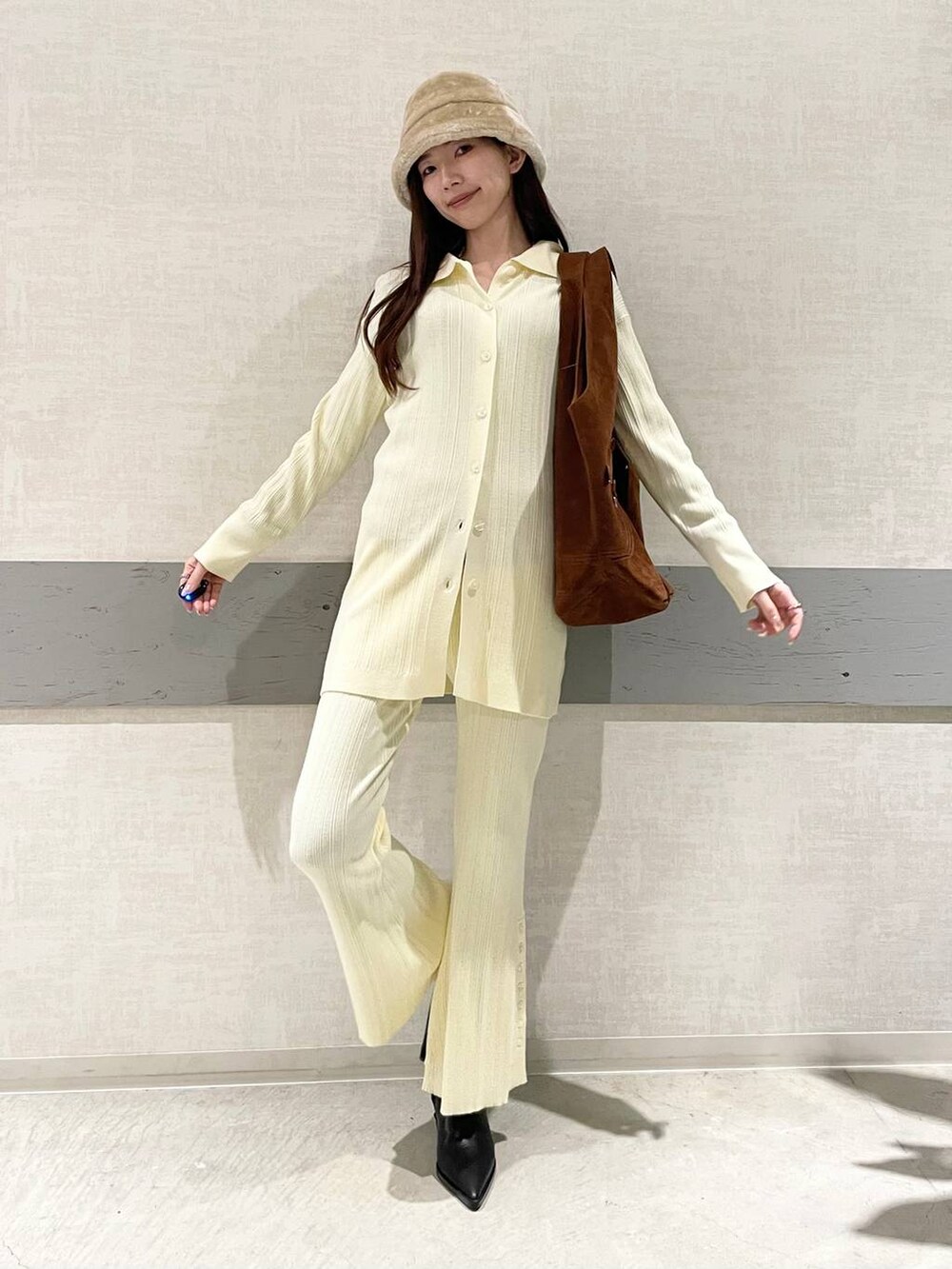 ブラック系のブーツ、ブラウン系のトートバッグ、イエロー系のセットアップを着用したレディースの冬コーディネートの2枚目の写真