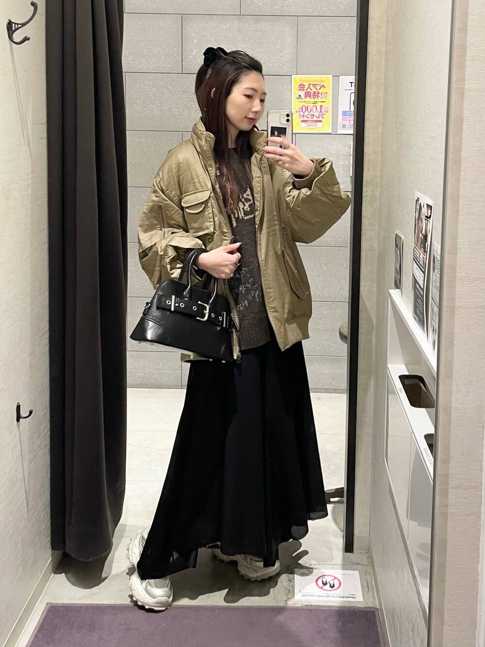 ホワイト系のスニーカー、ブラック系のボストンバッグ、ブラック系のスカートを着用したレディースの冬コーディネートの2枚目の写真