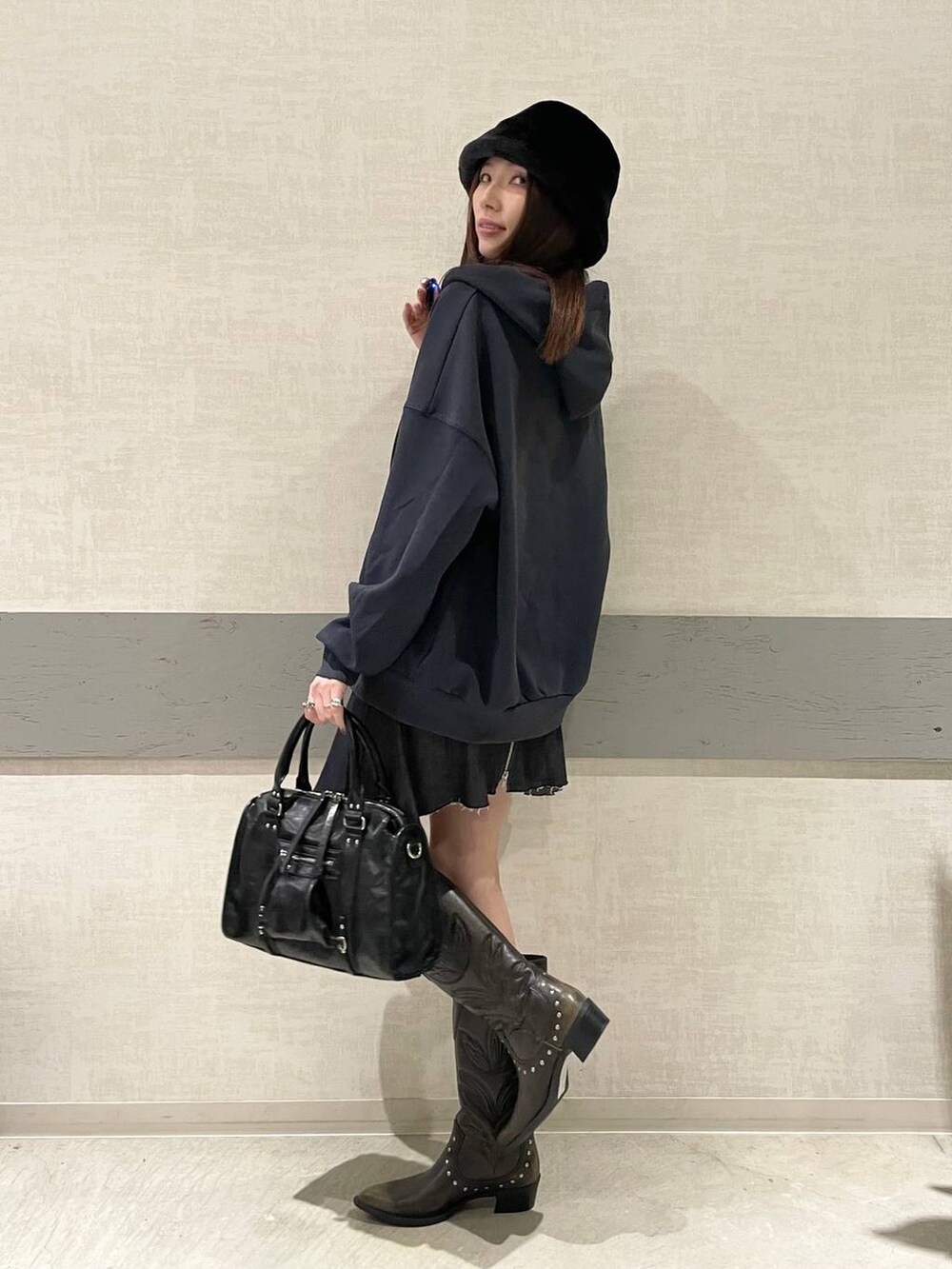 ブラック系のボストンバッグ、ブラック系のブーツ、ブルー系のパーカーを着用したレディースの冬コーディネートの3枚目の写真