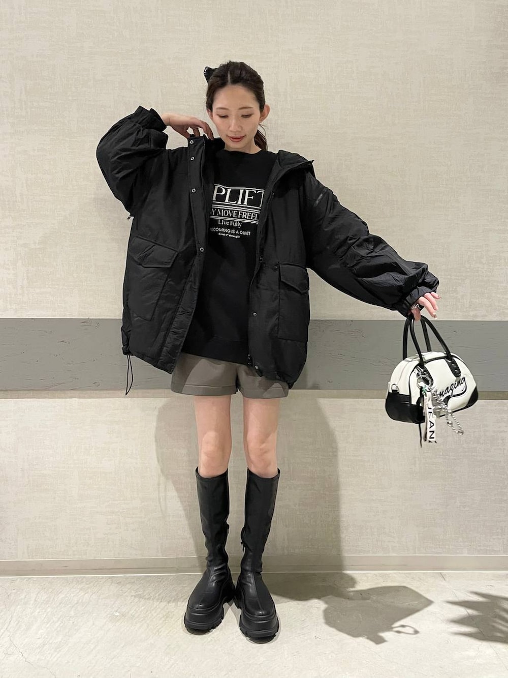 ブラック系のブルゾン、ホワイト系のショルダーバッグ、グレー系のその他パンツを着用したレディースの秋コーディネートの2枚目の写真