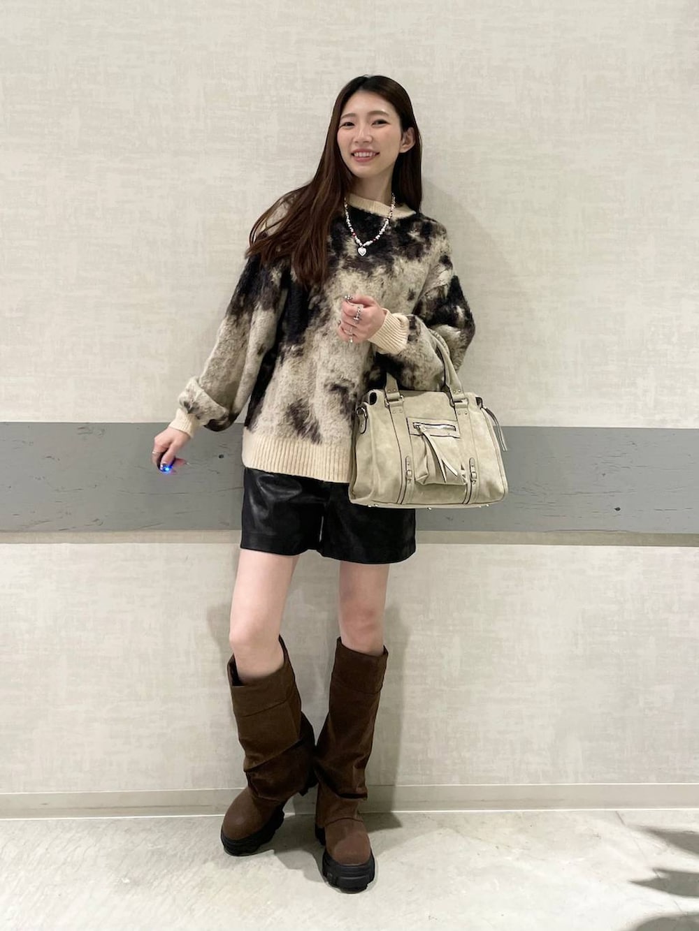 ブラウン系のニット/セーター、ベージュ系のボストンバッグ、ブラウン系のブーツを着用したレディースの秋コーディネートの4枚目の写真