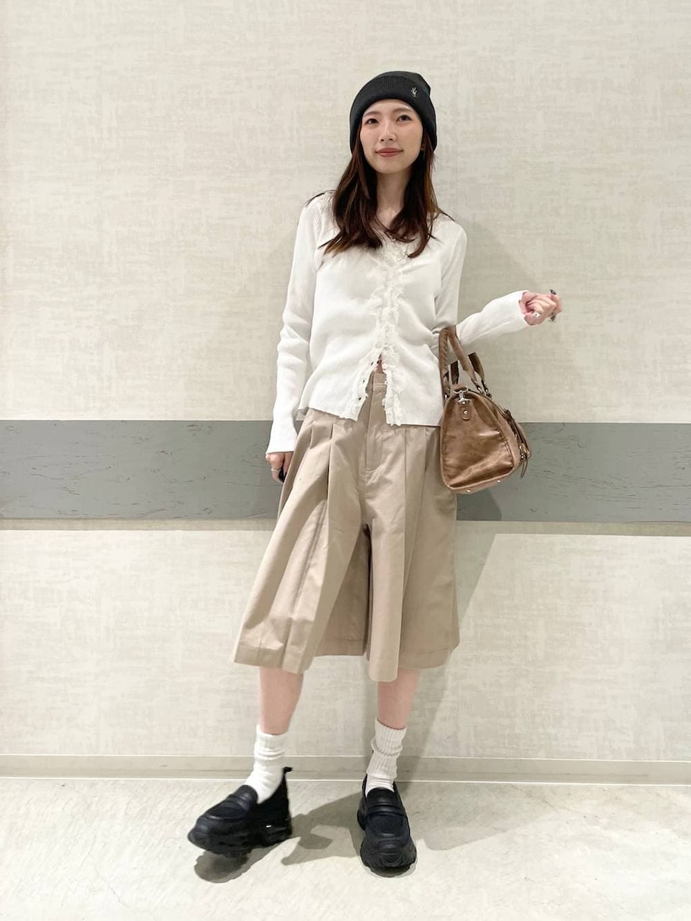 ブラック系のローファー、ブラウン系のボストンバッグ、ベージュ系のその他パンツを着用したレディースの春コーディネートの2枚目の写真