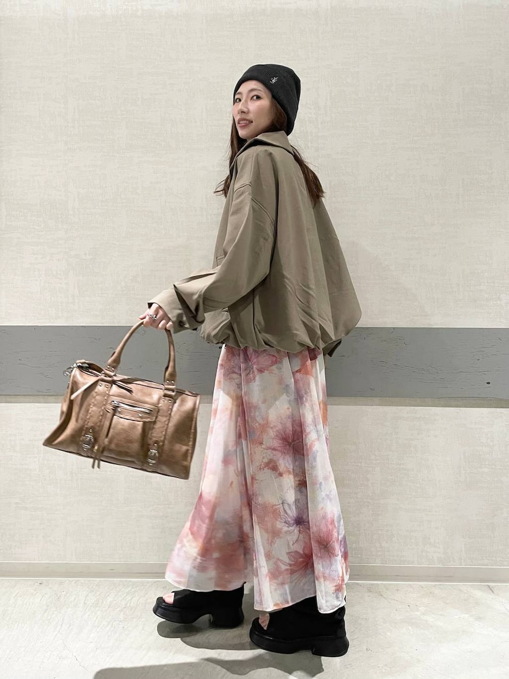 ホワイト系のタンクトップ、ブラウン系のボストンバッグ、ブラウン系のブルゾンを着用したレディースの春コーディネートの4枚目の写真