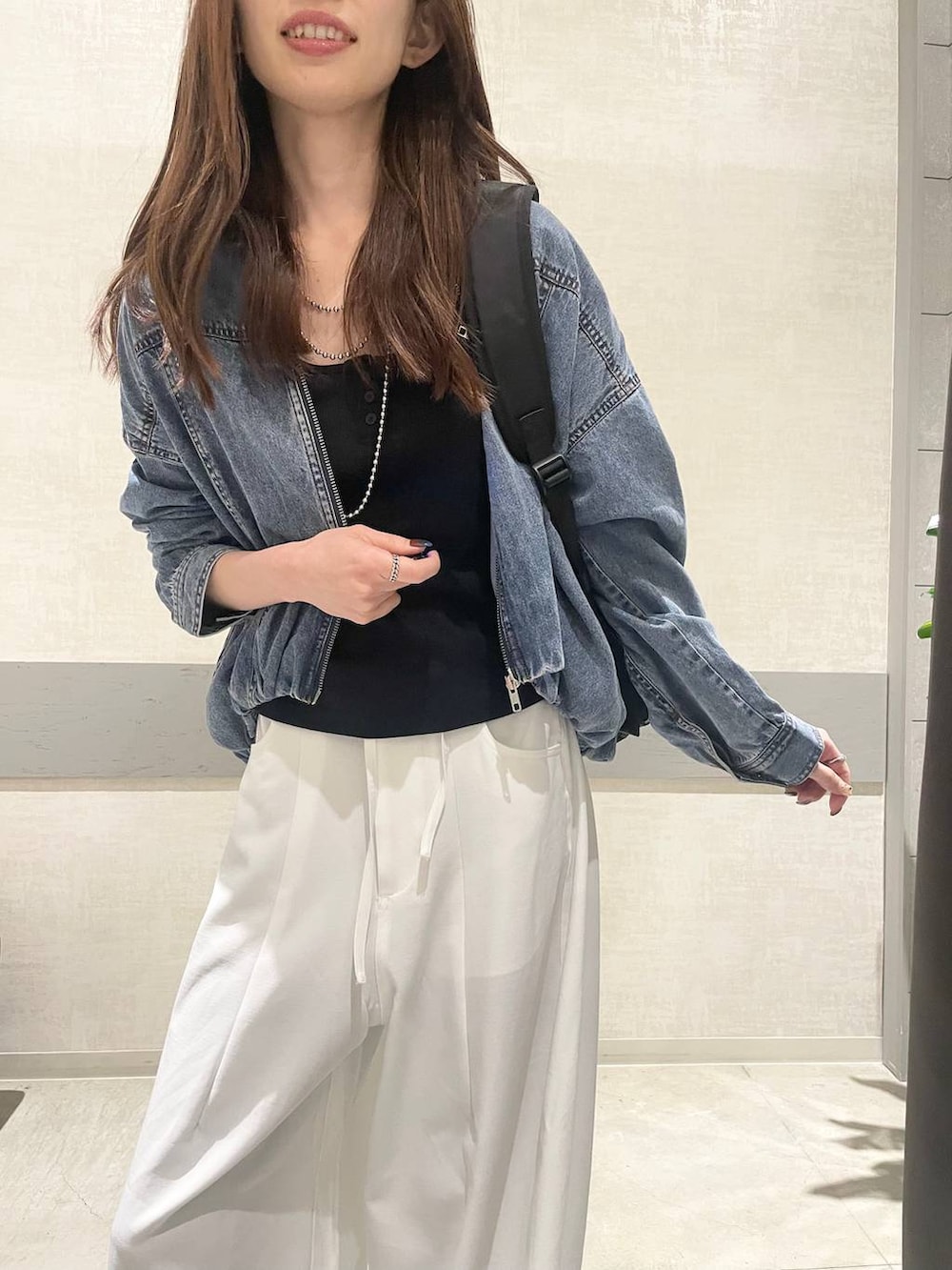 ブラック系のバックパック/リュック、ブラウン系のスニーカー、ブルー系のブルゾンを着用したレディースの春コーディネートの2枚目の写真