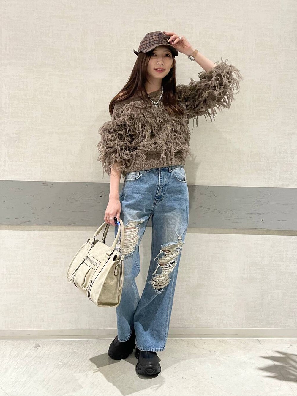 ベージュ系のボストンバッグ、ブラック系のブーツ、ブルー系のデニムパンツを着用したレディースの秋コーディネートの4枚目の写真