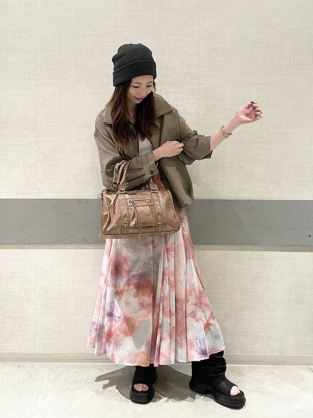 ホワイト系のタンクトップ、ブラウン系のボストンバッグ、ブラウン系のブルゾンを着用したレディースの春コーディネートの2枚目の写真