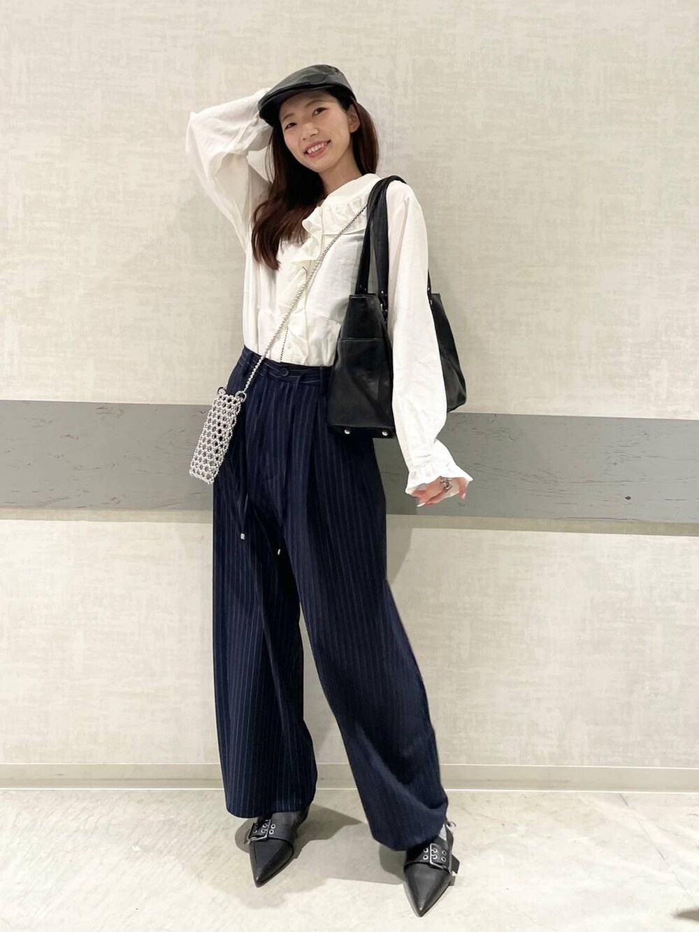 ブラック系のパンプス、ブルー系のスラックス、ブラック系のトートバッグを着用したレディースの春コーディネートの4枚目の写真