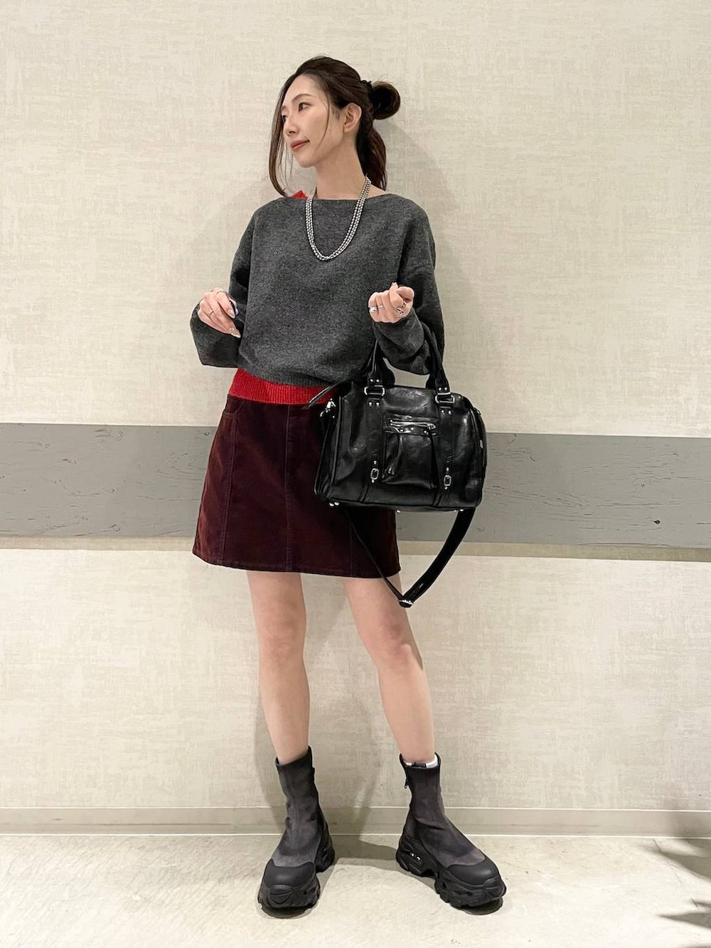 ブラック系のボストンバッグ、グレー系のブーツ、グレー系のニット/セーターを着用したレディースの冬コーディネートの2枚目の写真