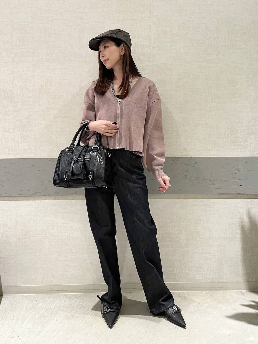 ブラック系のボストンバッグ、ブラック系のパンプス、ブルー系のデニムパンツを着用したレディースの冬コーディネートの5枚目の写真