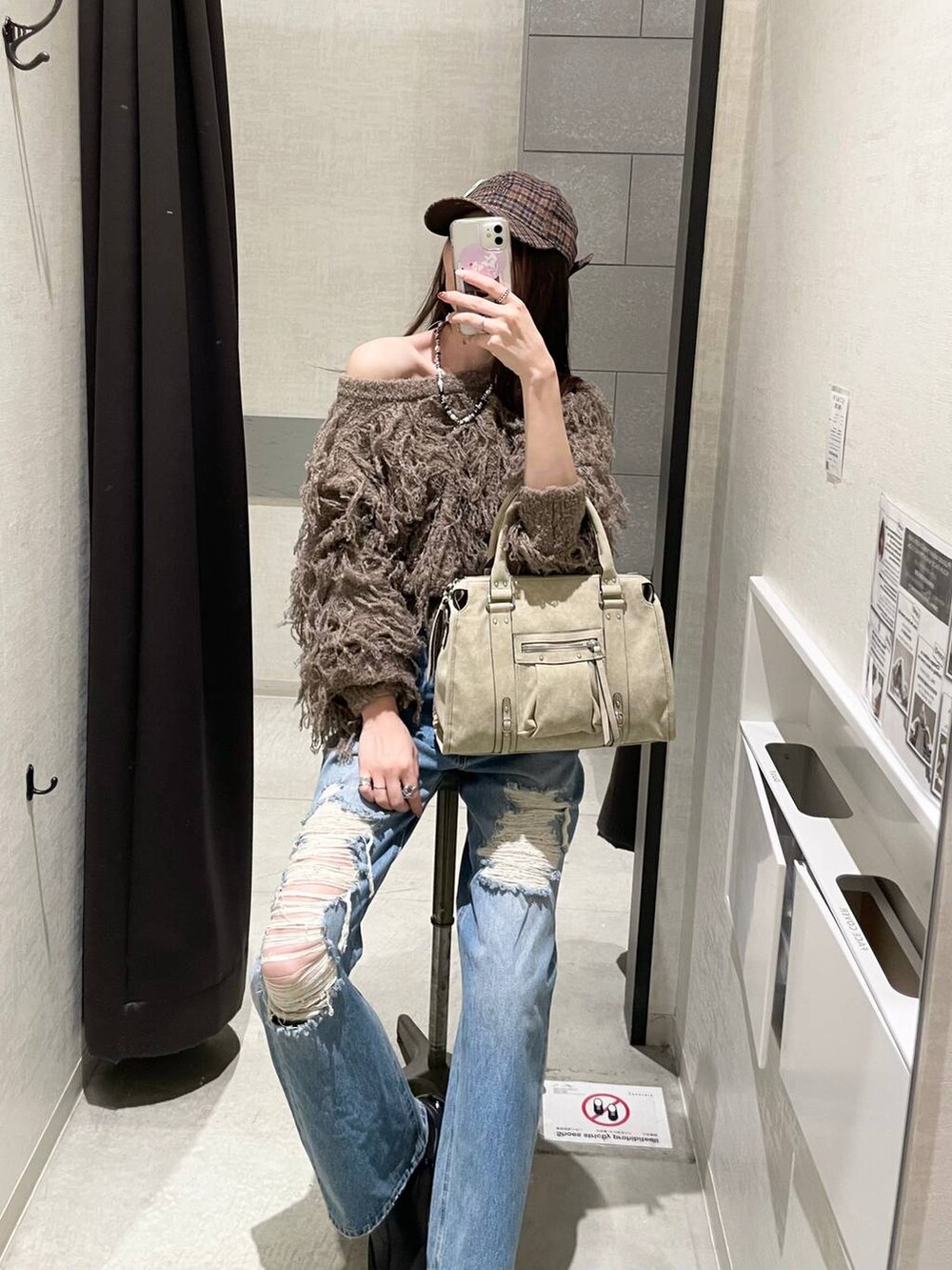 ベージュ系のボストンバッグ、ブラック系のブーツ、ブルー系のデニムパンツを着用したレディースの秋コーディネートの3枚目の写真