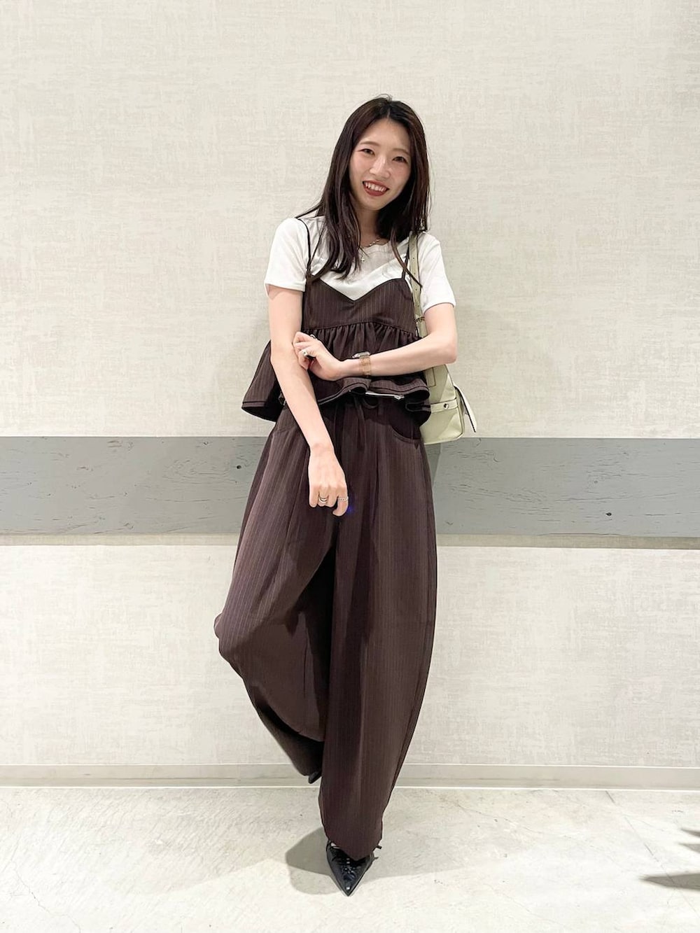 ブラック系のパンプス、ホワイト系のTシャツ/カットソー、ホワイト系のショルダーバッグを着用したレディースの夏コーディネートの2枚目の写真