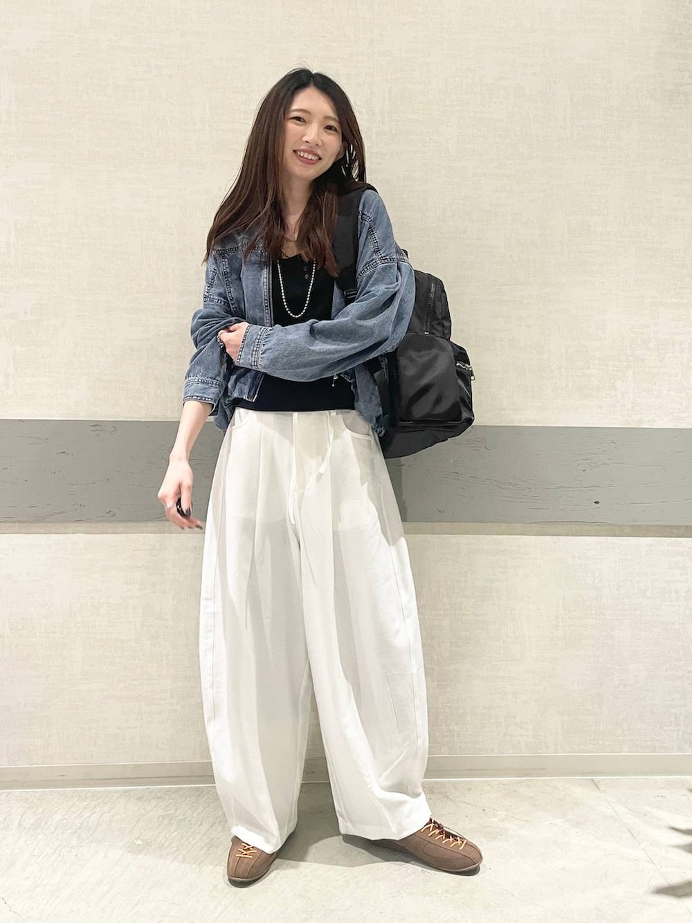 ブラック系のバックパック/リュック、ブラウン系のスニーカー、ブルー系のブルゾンを着用したレディースの春コーディネートの4枚目の写真