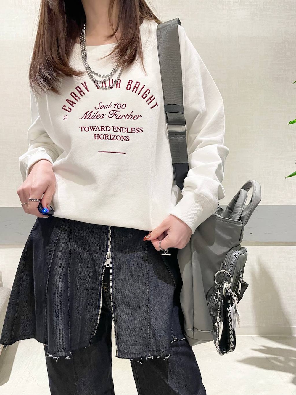 グリーン系のトートバッグ、ブラック系のパンプス、ブルー系のデニムパンツを着用したレディースの冬コーディネートの3枚目の写真