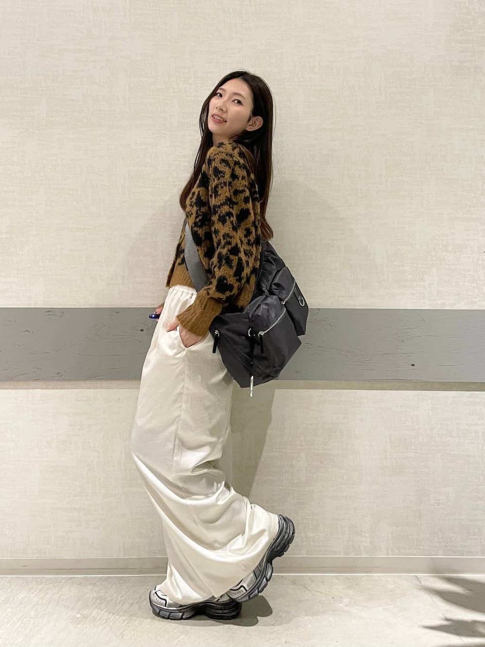 グレー系のショルダーバッグ、ホワイト系のスニーカー、ブラウン系のカーディガン/ボレロを着用したレディースの冬コーディネートの2枚目の写真