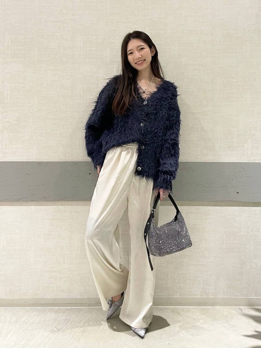 グレー系のパンプス、ブラック系のハンドバッグ、ブルー系のカーディガン/ボレロを着用したレディースの冬コーディネートの2枚目の写真