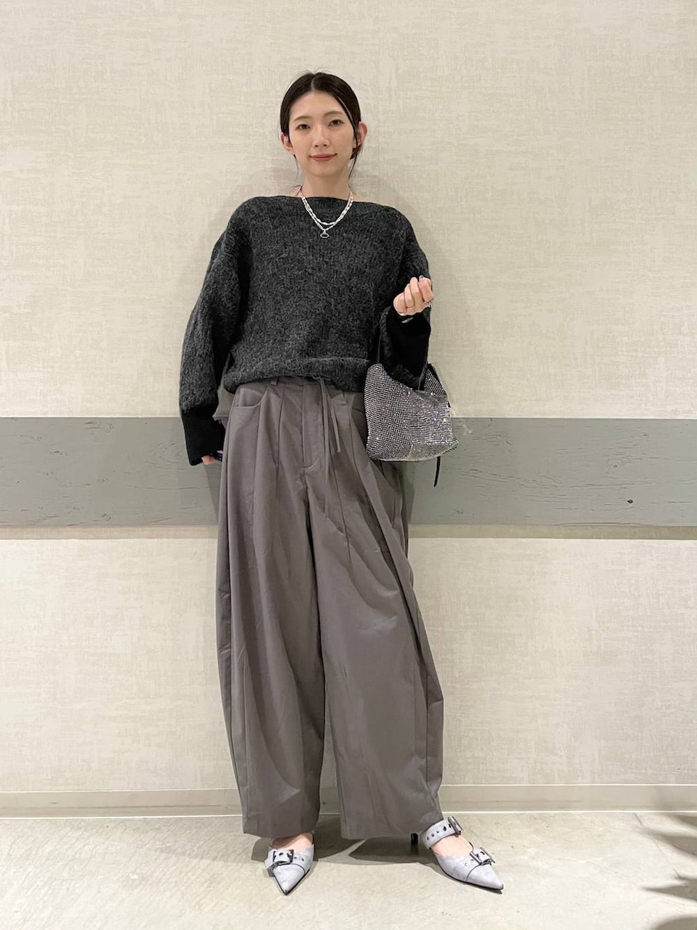 グレー系のスラックス、グレー系のパンプス、ブラック系のニット/セーターを着用したレディースの冬コーディネートの2枚目の写真