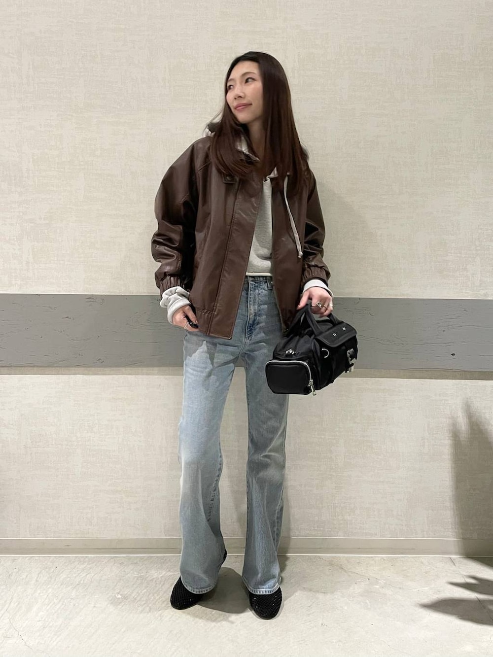 ブラック系のパンプス、ブラック系のボストンバッグ、ブルー系のデニムパンツを着用したレディースの冬コーディネートの4枚目の写真