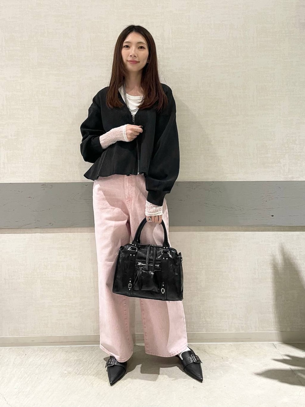 ブラック系のボストンバッグ、ブラック系のパンプス、ピンク系のデニムパンツを着用したレディースの冬コーディネートの4枚目の写真