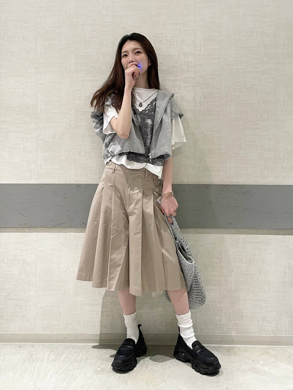 ブラック系のローファー、シルバー系のショルダーバッグ、グレー系のベストを着用したレディースの春コーディネートの4枚目の写真