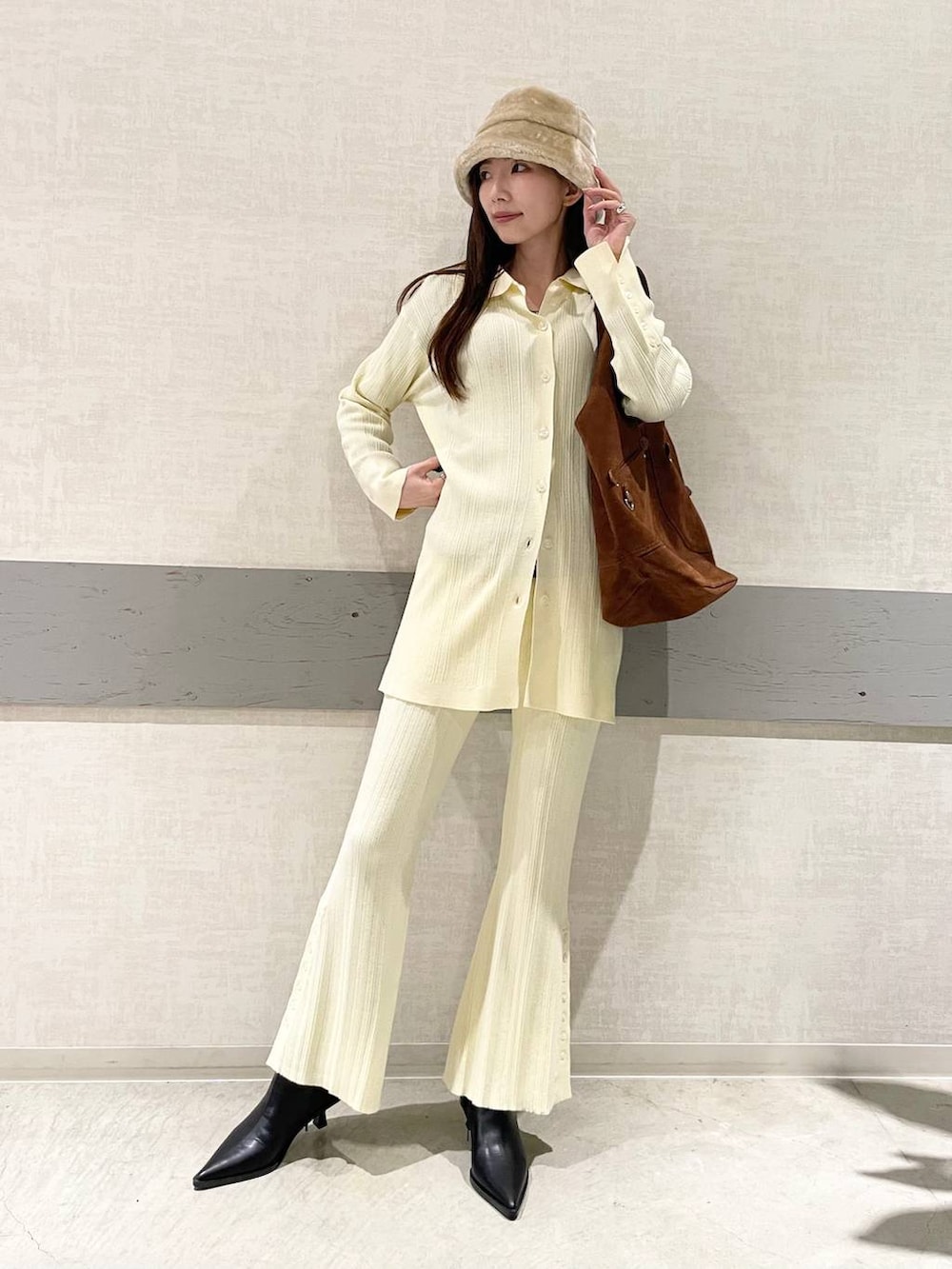 ブラック系のブーツ、ブラウン系のトートバッグ、イエロー系のセットアップを着用したレディースの冬コーディネートの5枚目の写真