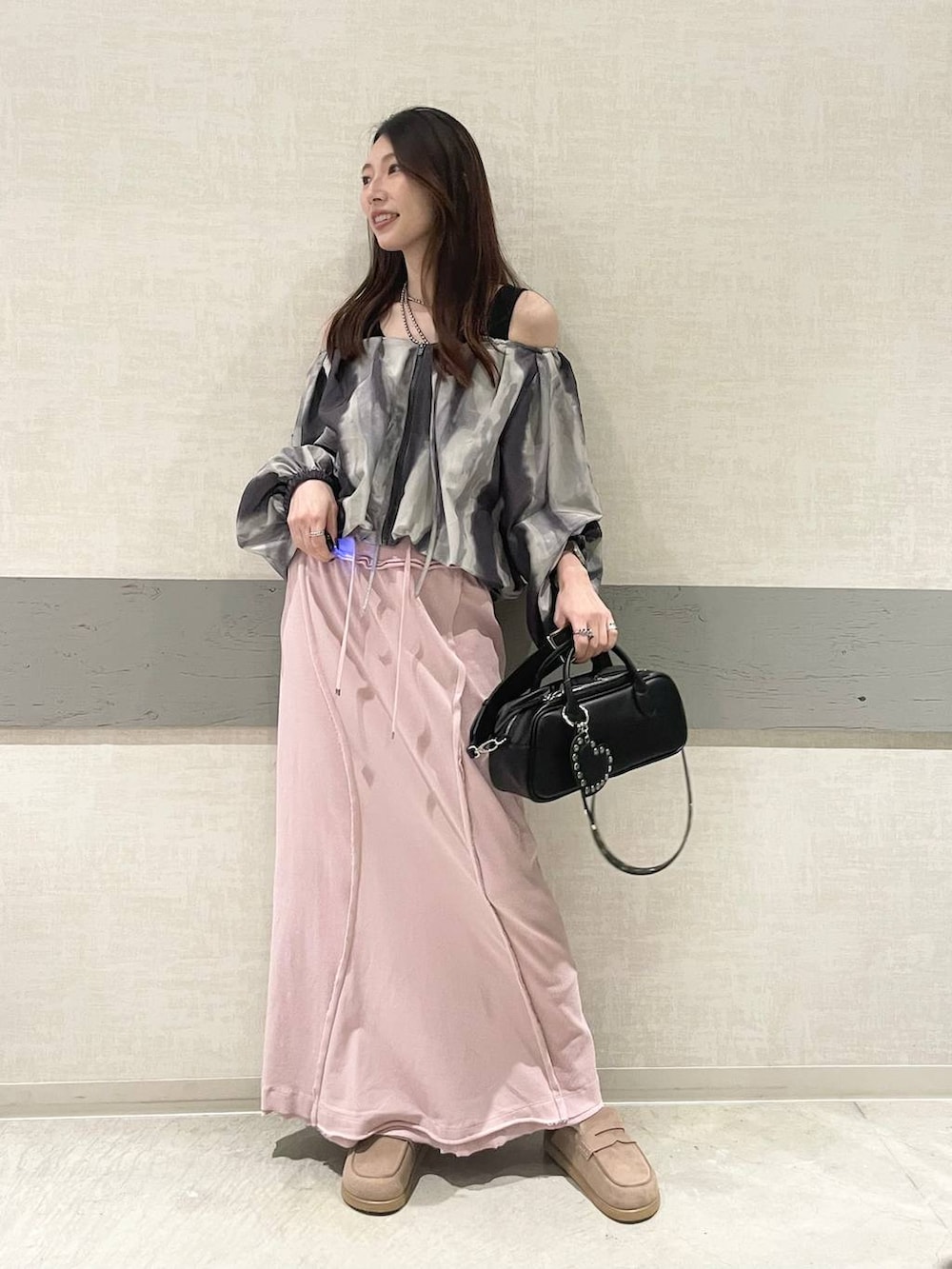 ブラック系のボストンバッグ、ベージュ系のローファー、ピンク系のスカートを着用したレディースの春コーディネートの4枚目の写真