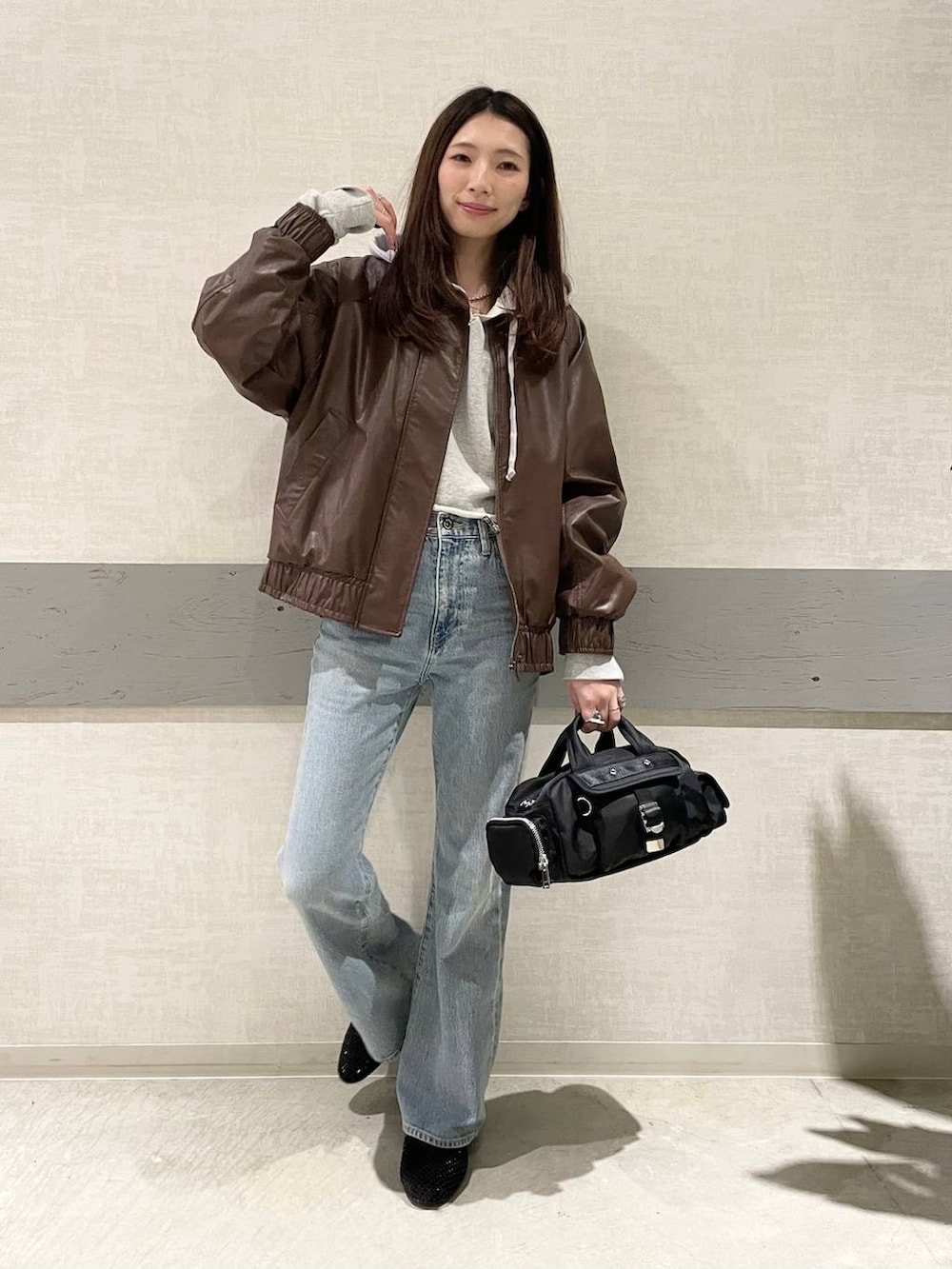 ブラック系のパンプス、ブラック系のボストンバッグ、ブルー系のデニムパンツを着用したレディースの冬コーディネートの2枚目の写真