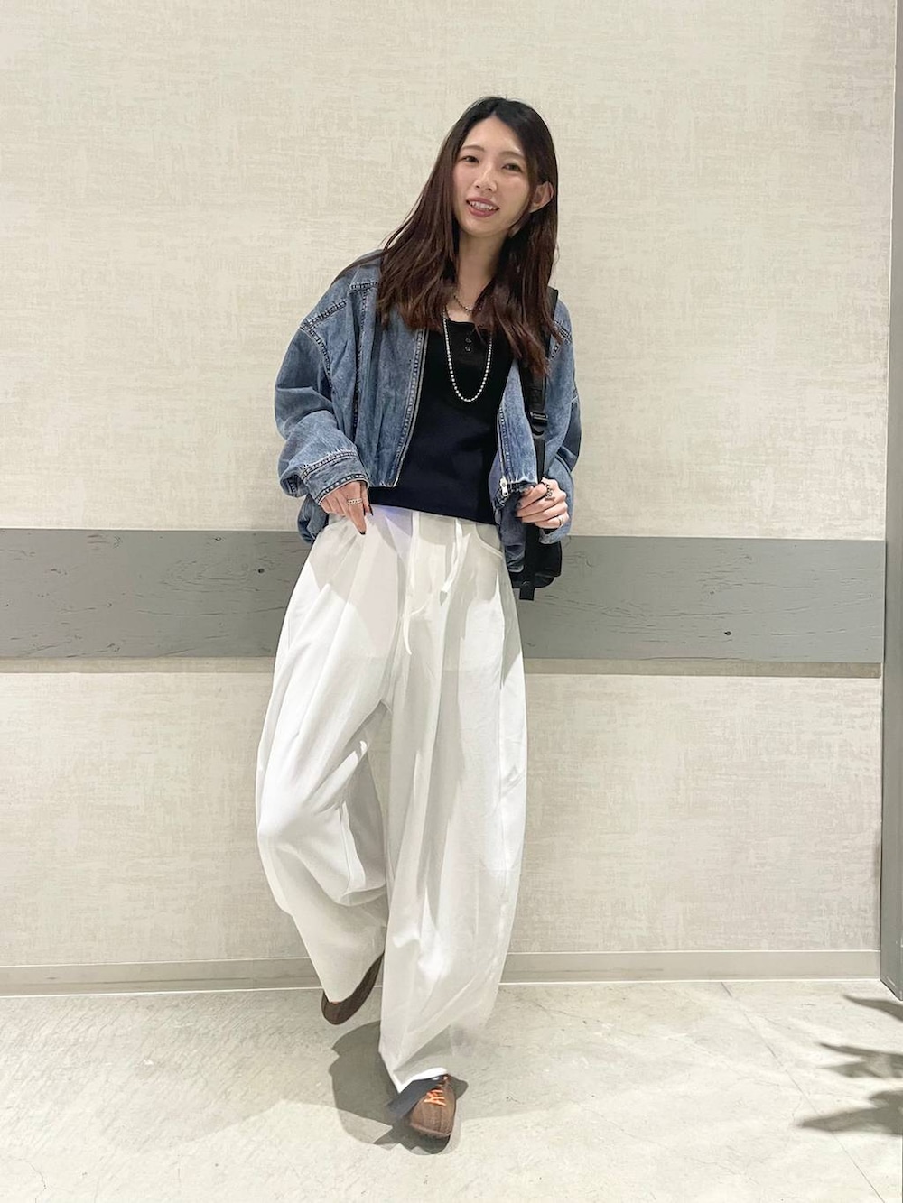 ブラック系のバックパック/リュック、ブラウン系のスニーカー、ブルー系のブルゾンを着用したレディースの春コーディネートの3枚目の写真