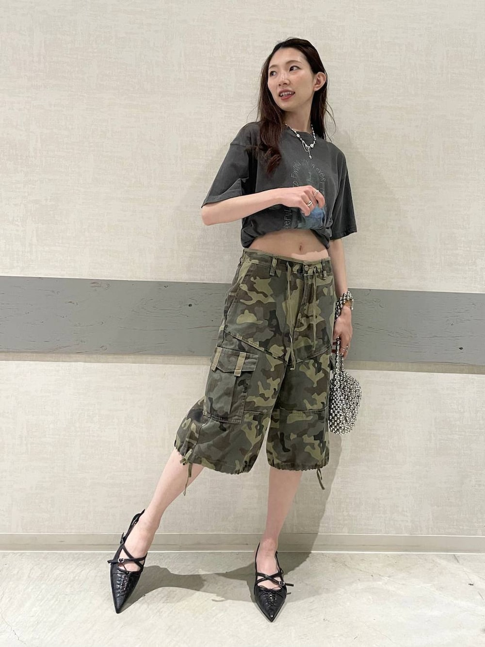 グレー系のTシャツ/カットソー、シルバー系のハンドバッグ、ブラック系のパンプスを着用したレディースの夏コーディネートの2枚目の写真