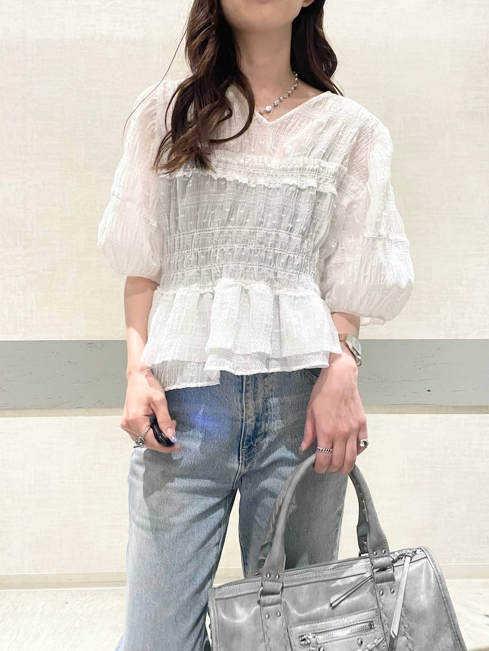 ブルー系のデニムパンツ、ブルー系のボストンバッグ、ホワイト系のサンダルを着用したレディースの春コーディネートの6枚目の写真