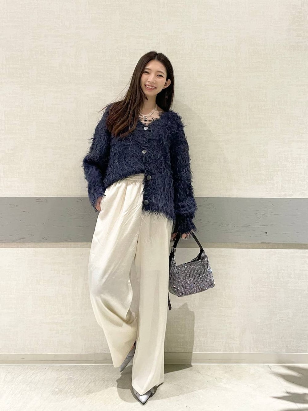 グレー系のパンプス、ブラック系のハンドバッグ、ブルー系のカーディガン/ボレロを着用したレディースの冬コーディネートの3枚目の写真