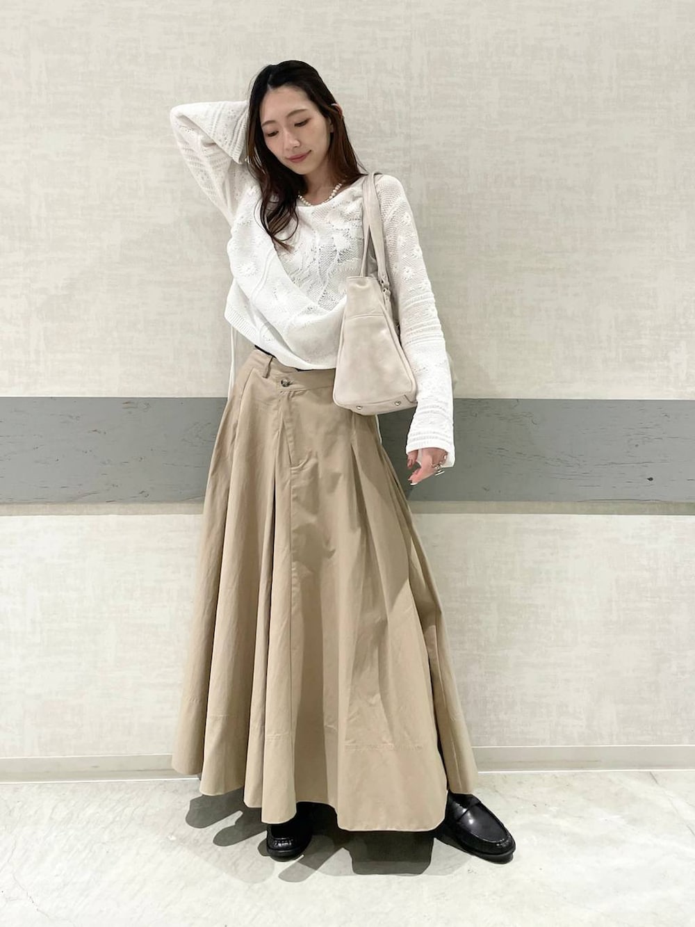 ホワイト系のトートバッグ、ベージュ系のスカート、ブラック系のローファーを着用したレディースの春コーディネートの2枚目の写真